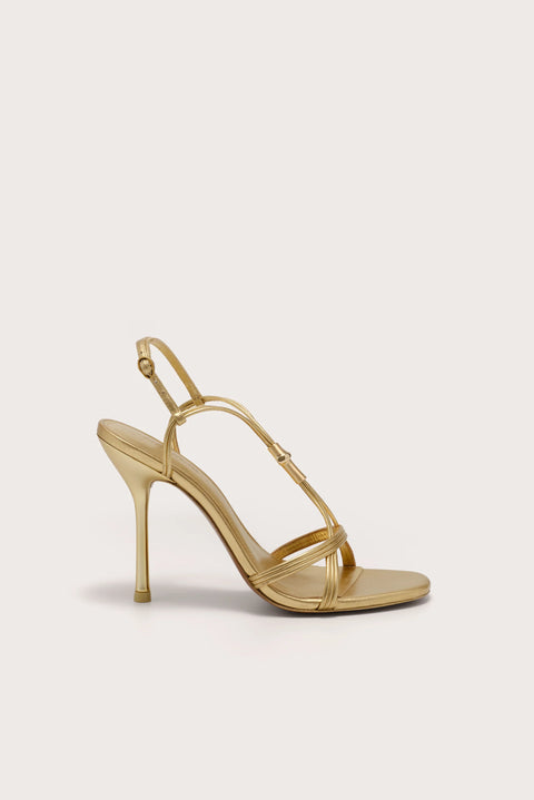 Side profile of a strappy gold stiletto heel that features gold-toned bamboo hardware.