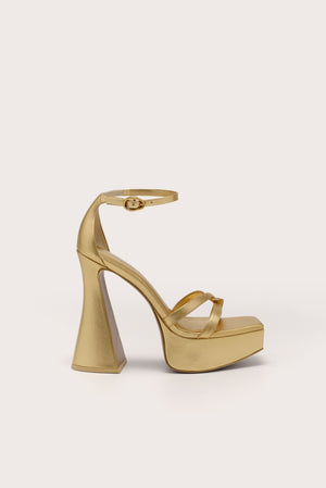 Side profile of a metallic gold platform sandal with crisscross toe straps, and ankle strap, and a 5.5" heel.