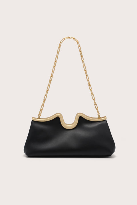 Black handbag with gold chain strap on a light beige background