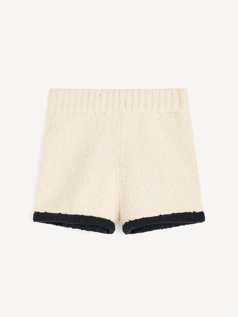 Flat lay of cream top and shorts with a black trim along on a white background.