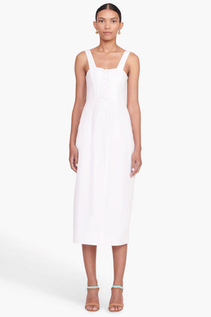 Full body view of a model facing the camera in the white midi dress with lace up bodice