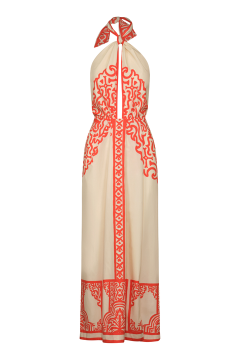 A cream-colored halter maxi dress with vibrant red-orange traditional patterns and borders, shown on a white background.