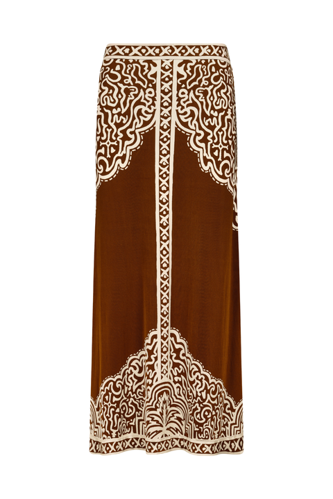 A brown midi skirt with intricate cream-colored bohemian-style embroidery, featuring ornate patterns at the waistband and hem, shown against a plain white background.
