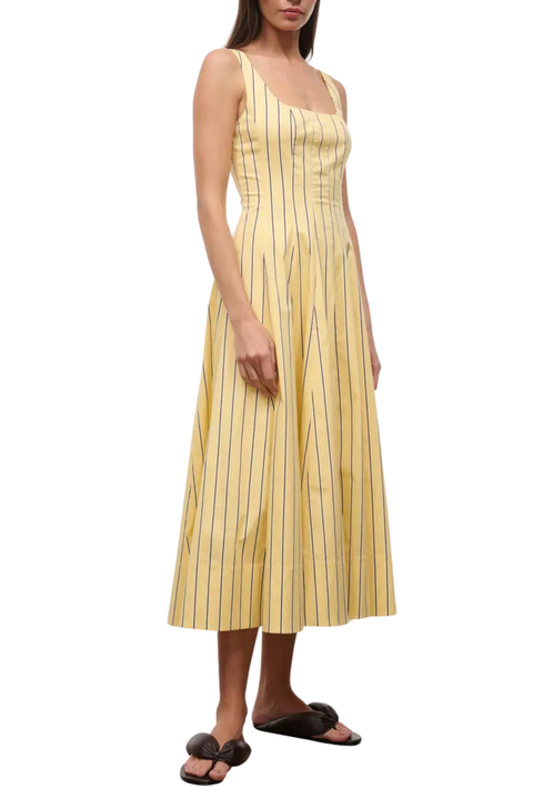 Woman wearing a long yellow striped dress with a red lobster design on a white background side angle