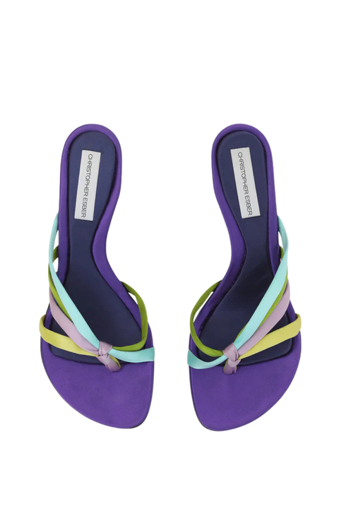 A pair of purple slide sandals with multi-colored straps in mint green, yellow, and lavender, shown from a top-down view on a white background. The insole features a white label with the brand name