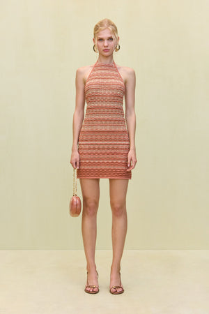 Woman wearing an knit mini dress that features a high neck, made of orange tonal stripes.