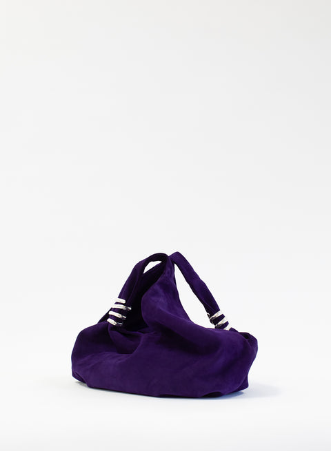 Side view of a purple suede handbag with silver accents on a white background