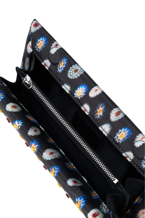 A close-up of a black clutch with a colorful ikat pattern, shown open to reveal a black interior and silver zipper.