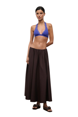 A model wearing a two-piece swim set consisting of a dark brown maxi skirt and a royal blue halter bikini top with silver star embellishments, set against a plain white background.