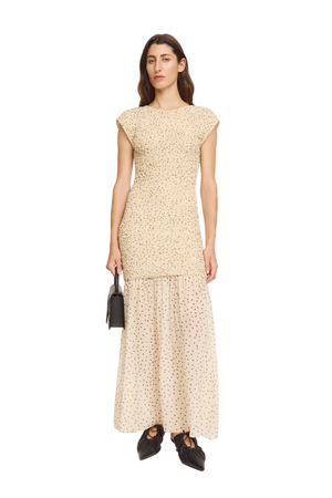 Woman wearing a bodycon patterned dress holding a black handbag on a white background