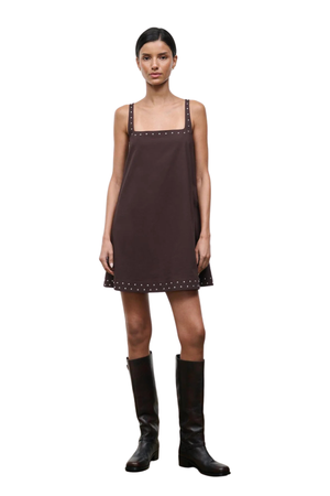 Woman wearing a brown sleeveless square neck mini dress with studs on a white background