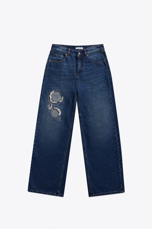 Front of dark wash blue jeans with a decorative crystal and chain cut outs  on a white background