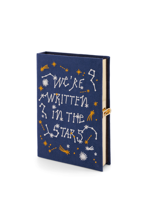 A navy blue book clutch with white and gold celestial illustrations and the phrase 'WE'RE WRITTEN IN THE STARS' on the cover, shown on a white background.