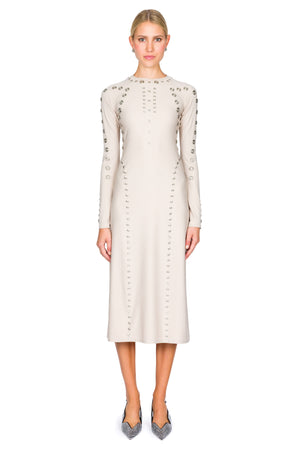 Woman wearing a cream midi dress with decorative snaps on a white background