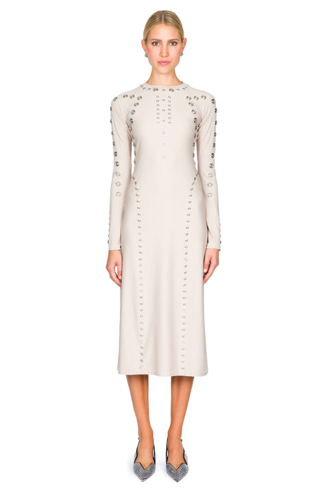 Woman wearing a cream midi dress with decorative snaps on a white background