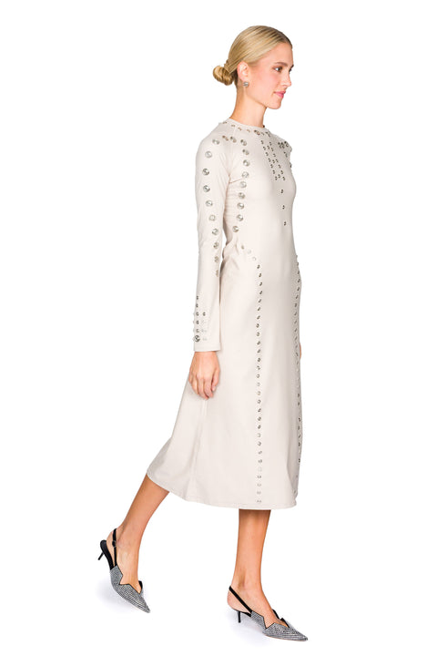 Woman stepping to the side in  a long, light-colored dress with snap details on a white background