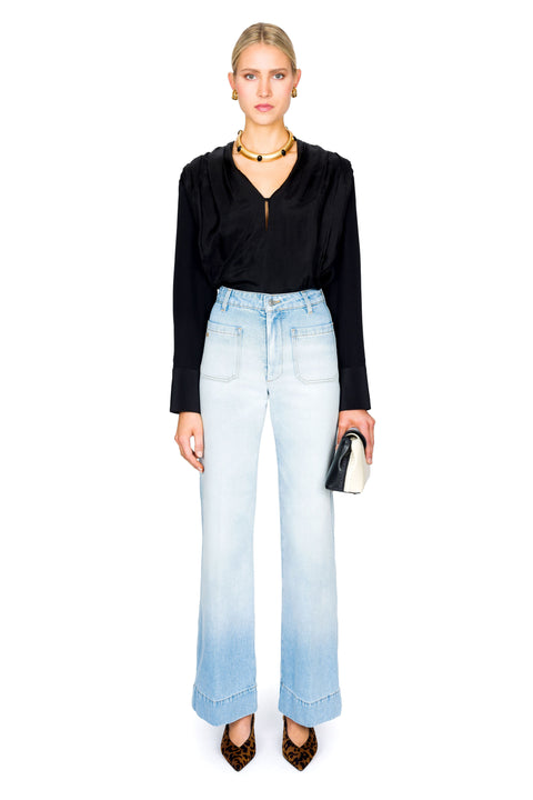 Woman wearing a black top and light blue jeans on a white background