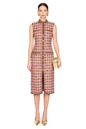 Woman wearing a pink check patterned midi dress with buttons down the front with a gold clutch on a white background