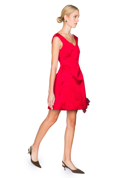 Woman walking to the right wearing a red mini dress on a white background
