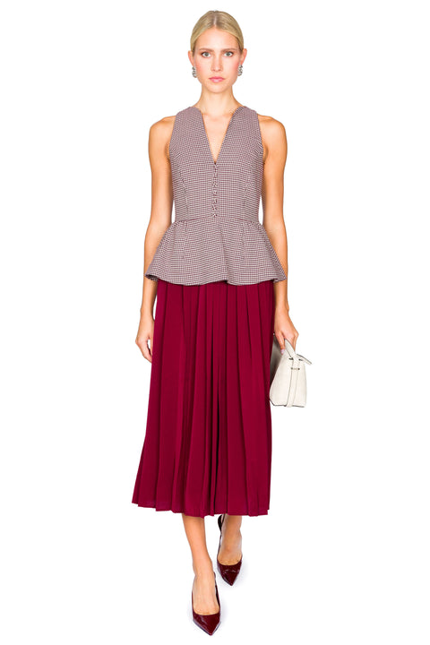 Woman walking a sleeveless houndstooth patterned top and red skirt dress on a white background.