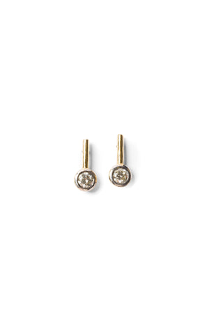 A pair of round diamond studs suspended on a gold stick and set in a a white gold bezel.