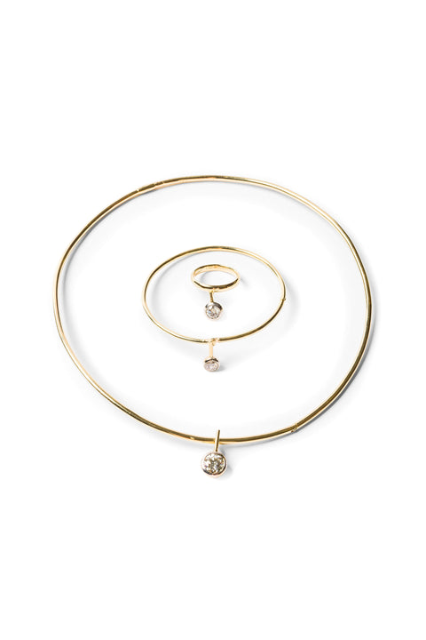 A gold ring with a round diamond dangle, a gold bangle with a round diamond dangle, and a gold neck wire with a around diamond dangle in concentric circles.