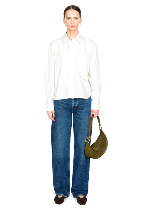 Woman wearing a green shirt and blue jeans, holding a green bag on a white background
