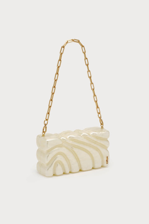 Textured pearlescent clutch with ornate design with chain strap showing staged off-center.