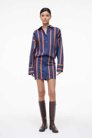 Woman wearing a blue and orange striped long sleeve mini dress with brown boots.
