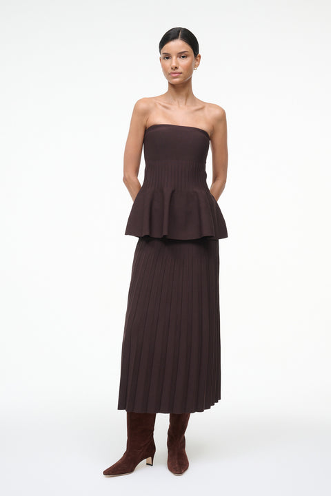 Woman wearing a brown strapless peplum dress on a white background