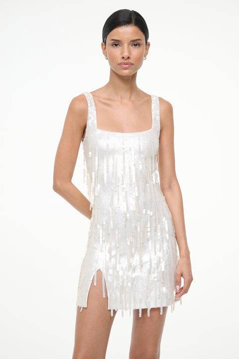 Close up of a woman wearing a white sequin fringe mini dress on a white background