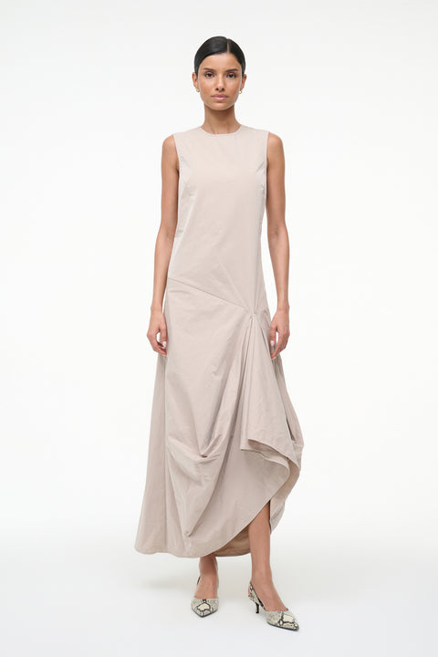 Woman wearing a beige sleeveless asymmetrical dress on a white background