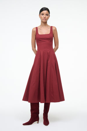 Woman wearing a red dress and matching knee-high boots on a white background