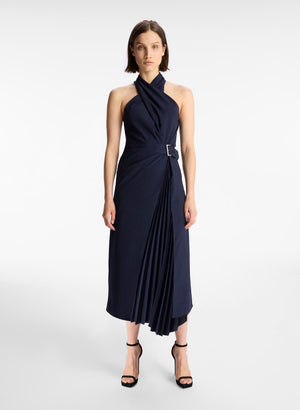 Model facing the camera in the navy midi dress with crossover halter neckline