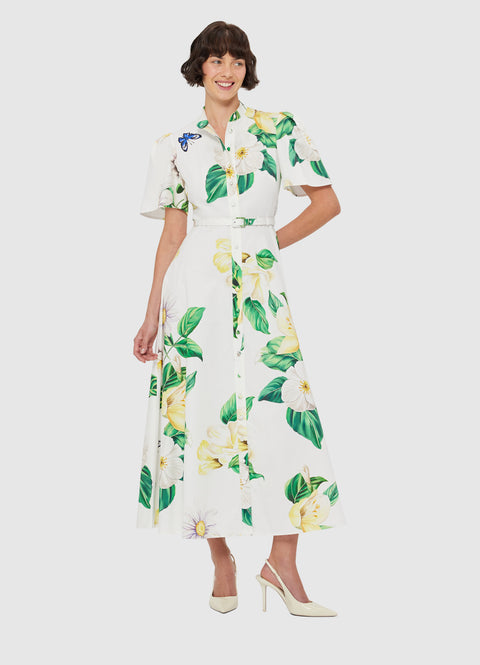 Woman poses in white midi dress with floral print and belt at waist.