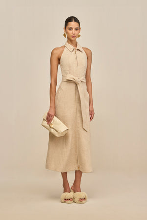 Woman wearing a beige dress with a belt on a beige background