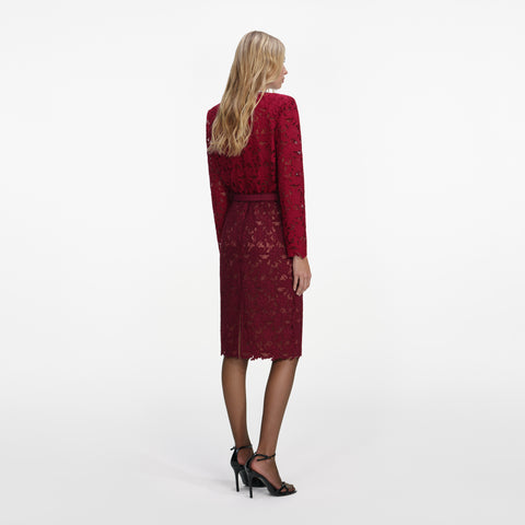 Woman showing the back of a red lace long sleeve top and red lace midi skirt with a white background