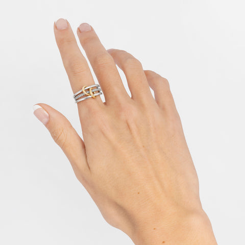 A woman's hand wearing a Spinelli Kilcollin Sonny ring that features three 1.7mm sterling silver bands, one with pave gray diamonds, connected by two 18k yellow gold connectors.