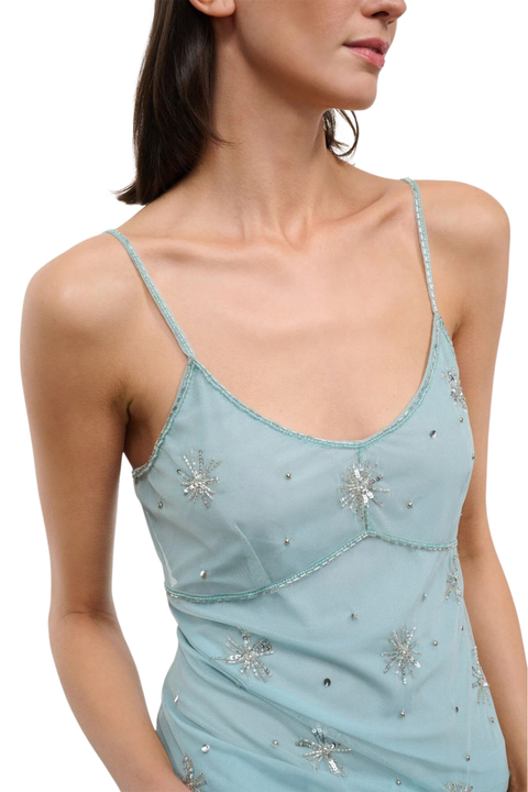Woman wearing a light blue denim tank top with embellishments on a white background front close up