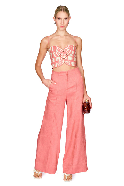 Woman wearing a strapless top with a geometric pattern and pink wide-leg pants on a white background