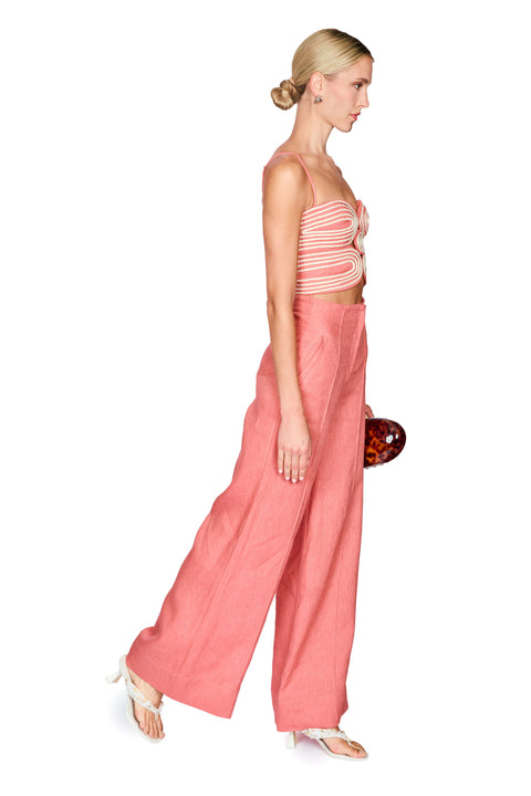 Woman wearing a pink strapless top and wide-leg pants on a white background