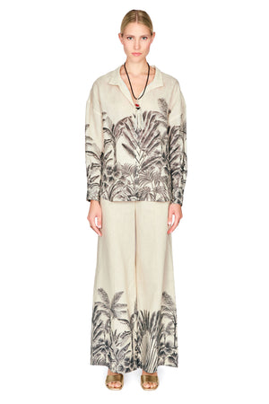 Woman wearing a patterned button down blouse and long pants on a white background