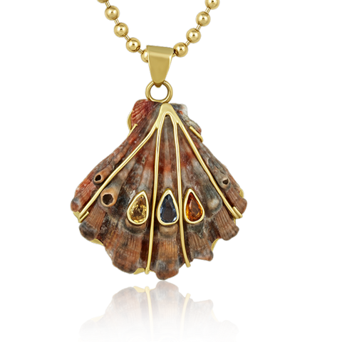 Shell pendant with gold accents and different colored gemstones on a white background