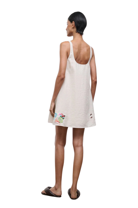 A woman facing the back wearing a mini dress with embroidered beach details