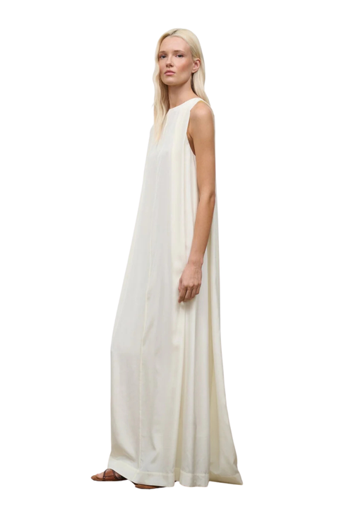 Woman wearing a white sleeveless maxi dress on a white background side angle