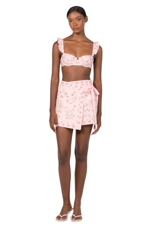 A woman wearing a pink multicolor swim cover up sarong with a side tie