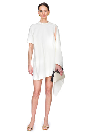 Woman wearing a white dress with a cutout design on one shoulder on a white background