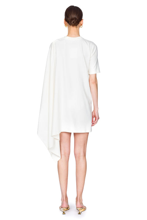 Woman wearing a white dress with a cutout design on one shoulder on a white background from the back.
