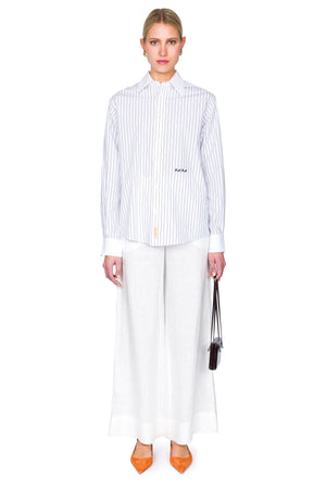Woman wearing a striped shirt and white pants on a white background