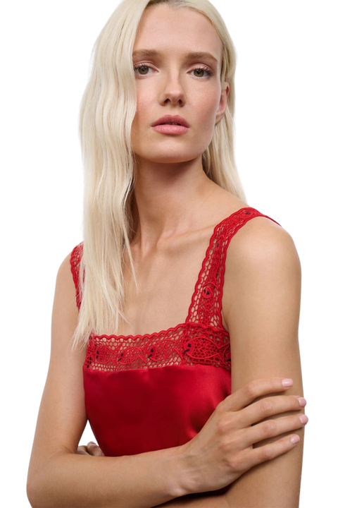 A woman wearing a red silk top with fish embroidery at the hem close up angle